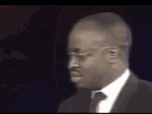 a man in a suit and tie is standing in front of a black background .
