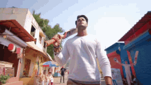 a man in a white shirt holds a cricket bat