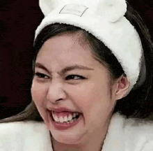 a close up of a woman wearing a white headband with ears making a funny face .
