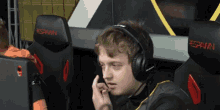 a man wearing headphones sits in a chair that says spawn on it