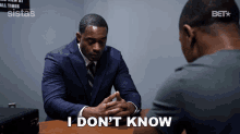 a man in a suit and tie sits at a table with another man and says i don t know