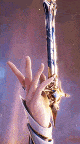 a person 's hand is holding a sword with a purple background