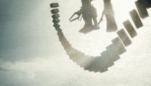 a shadow of a person is cast on a row of dominoes against a cloudy sky