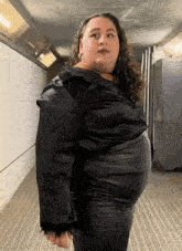 a woman is standing in a hallway wearing a black leather skirt and a black jacket .