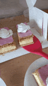 a slice of cake with pink frosting and whipped cream on top