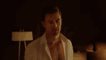 a shirtless man is sitting on a bed in a dark room looking at the camera .