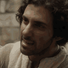 a man with curly hair and a beard is wearing a white robe