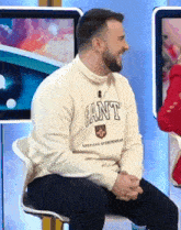 a man wearing a sweater that says gant is sitting on a chair