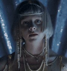 a woman with blonde hair and pearls on her shoulder