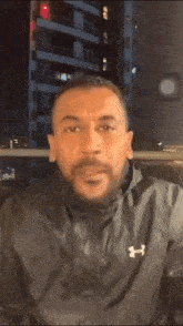 a man with a beard is making a funny face in front of a building at night