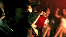 a man is drinking from a red cup with the letter s on it