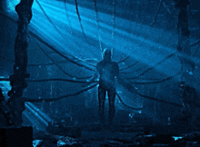a man is standing in a dark room with a blue light shining through the ceiling