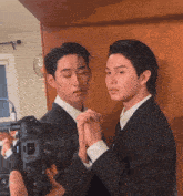 a man taking a picture of two men in suits with a canon camera
