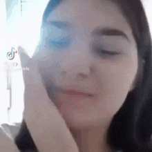 a close up of a woman 's face with her hand on her chin .