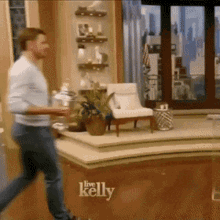 a man is running in front of a live kelly sign
