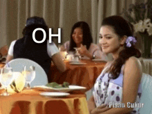 a woman is sitting at a table with a plate of food and a caption that says oh .