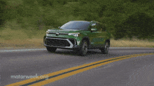 a green car is driving down a road with motorweek.org written on the bottom right