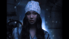 a woman wearing a hat and a necklace is looking at the camera .