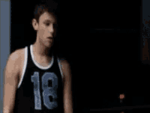 a young man wearing a black basketball jersey with the number 18 on it
