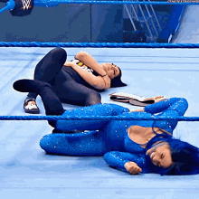 two women in blue wrestling outfits are laying on the ground