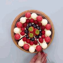a person is cutting a piece of cake with berries on top