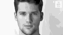 a black and white photo of a young man with a beard .