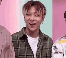 a young man wearing a plaid shirt and earrings is smiling .