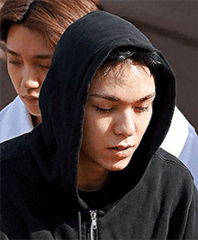 a young man wearing a black hoodie is looking down