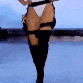 a woman in a swimsuit and black boots is walking on a stage