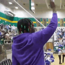 a man in a purple hoodie holds up a basketball hoop