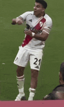 a soccer player with the number 21 on his shorts is standing on the field