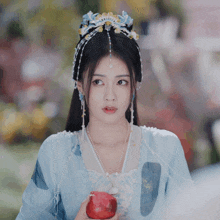 a woman in a blue dress is holding an apple in her hand