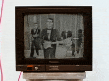 a panasonic television shows a man playing a guitar in a band
