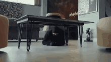 a man is laying on the floor under a coffee table