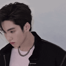 a close up of a man wearing a black jacket and a necklace