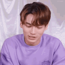 a close up of a young man wearing a purple sweatshirt .