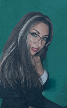 a woman wearing glasses and a black jacket is smiling for the camera