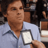 a man in a blue shirt is holding a badge that says m.j. smith