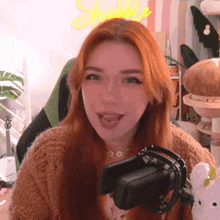 a woman with red hair is holding a cell phone in front of a microphone and smiling .