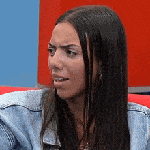 a woman is sitting on a red couch making a funny face .