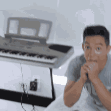 a man covering his mouth with his hands in front of a keyboard that says yamaha on it