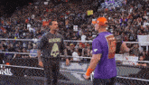 a man wearing a ramones shirt talks to a man wearing a purple shirt