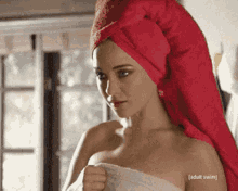 a woman with a towel wrapped around her head is standing in front of a window .