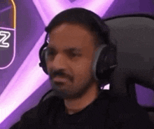 a man wearing headphones is sitting in a chair and making a funny face .