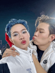 a man with blue hair kisses another man on the lips
