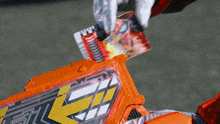 a person is putting a card into an orange box with a yellow arrow on it