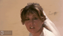 a woman in a wedding dress with a veil on her head looks at the camera