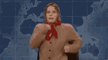 a woman in a sweater and scarf is standing in front of a world map .