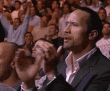 a man in a suit is sitting in a crowd of people .