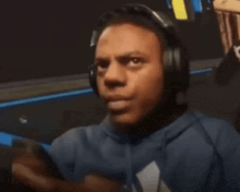a man wearing headphones and a blue hoodie is looking at something